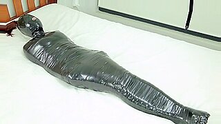 Asian milf mummified in red, experiencing extreme sensory deprivation.