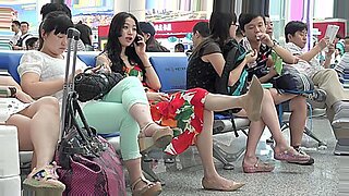 アジアの美女が、公共の空港での出会いで彼女の足を披露する。