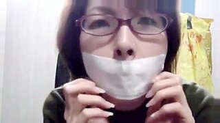 Bella asiatica esplora il BDSM con auto-tape gagging e bondage