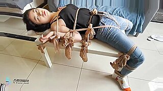 一个被捆绑的亚洲宝贝穿着长筒袜被堵住嘴并被挑逗。