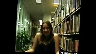 一个年轻的大学女孩和她的朋友在图书馆里淘气。