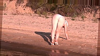 Una rubia sexy cubierta de sol se desnuda junto al océano.