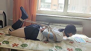 Asian beauty restrained and teased in intense bondage scenario.